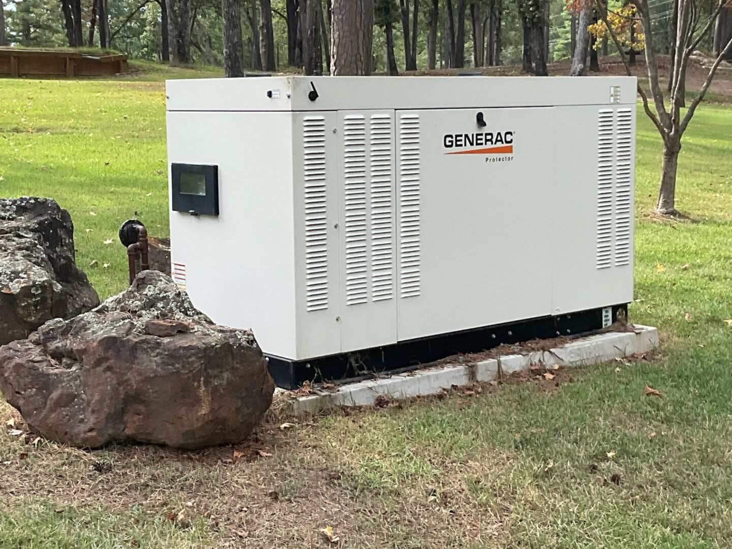 A white generator sitting next to a tree.